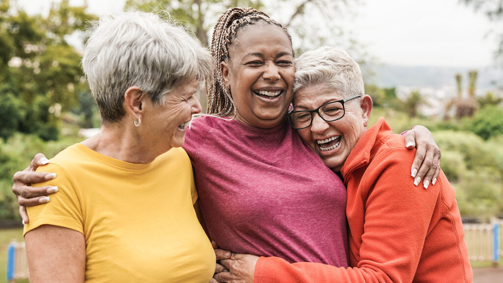 Three women hugging and laughing together.
