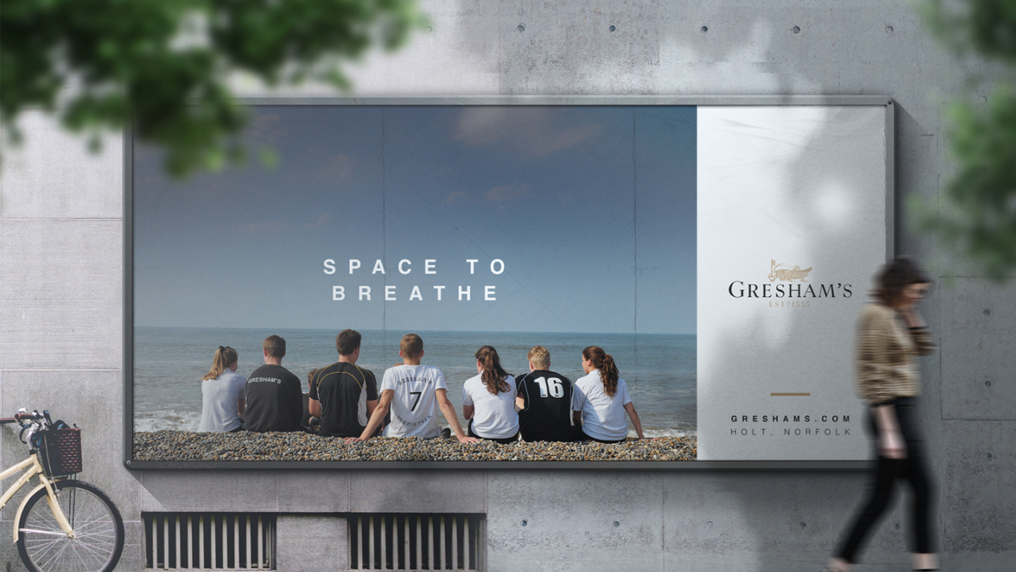 Large billboard showing Gresham's brand campaign, Space To Breathe which shows and image of students sat on a Norfolk beach. 