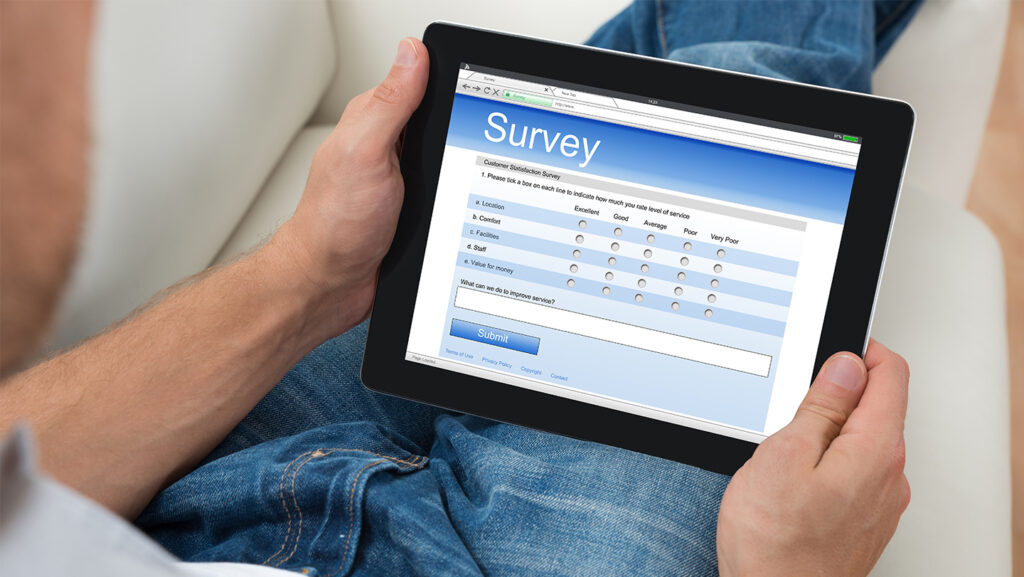 Hands holding an ipad, looking at an online survey.